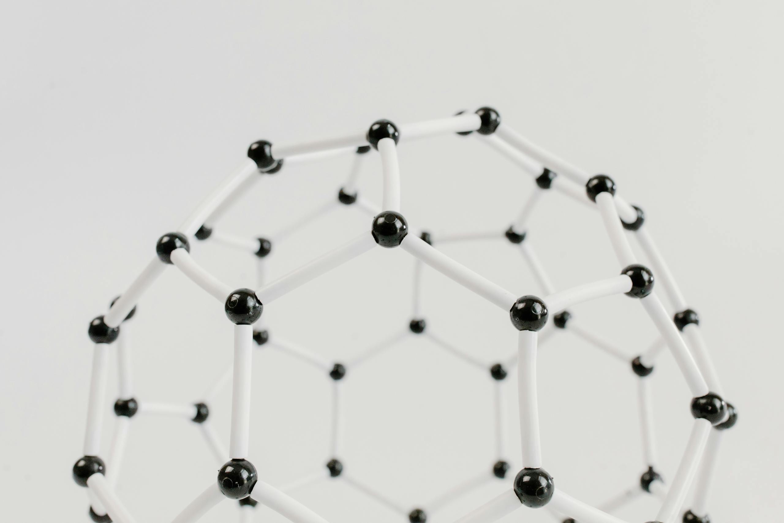 Close-up of a geometric molecular structure model with black and white connections on a light background.