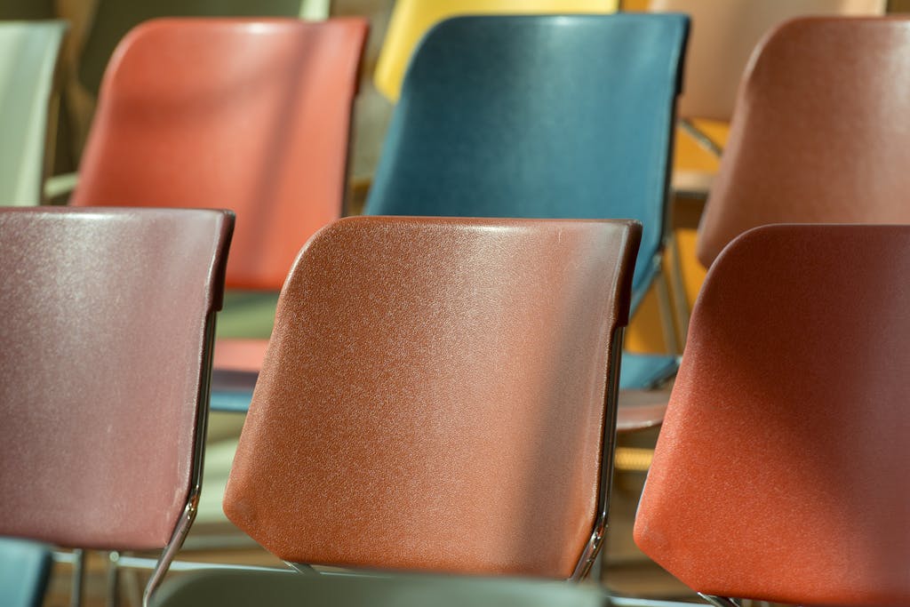 Close-up view of colorful plastic chairs arranged in soft sunlight.