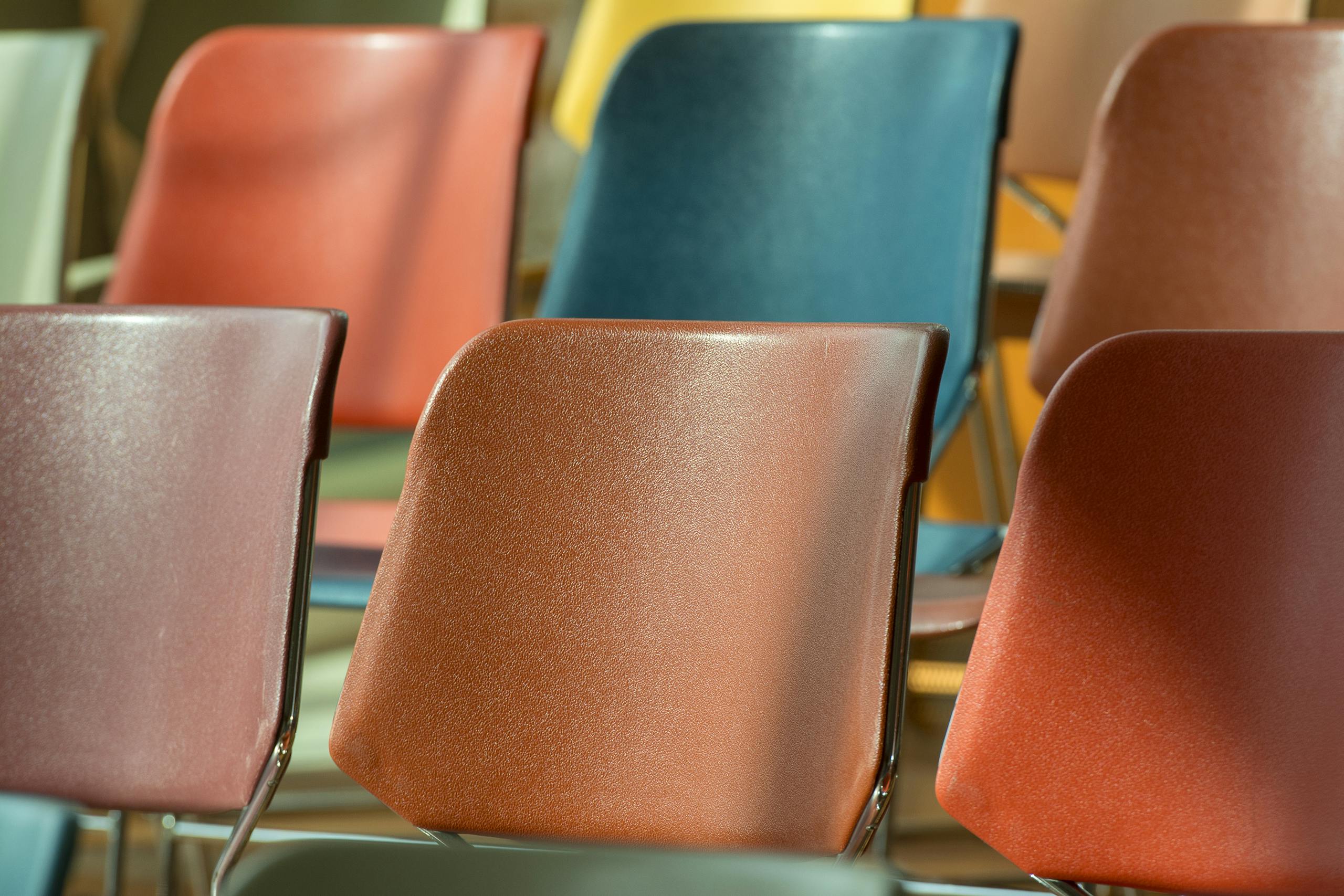 Close-up view of colorful plastic chairs arranged in soft sunlight.